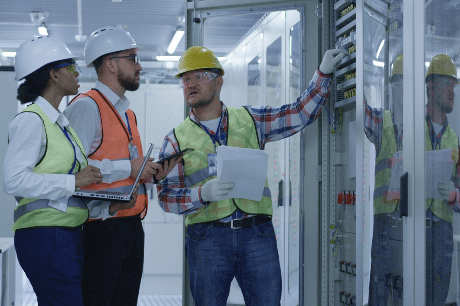 Three people in hard hats looking at electrical panel
