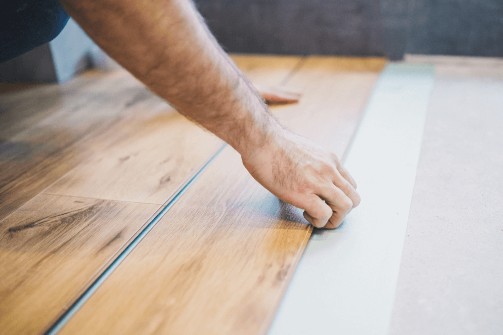 Man's hands laying a wooden board as flooring