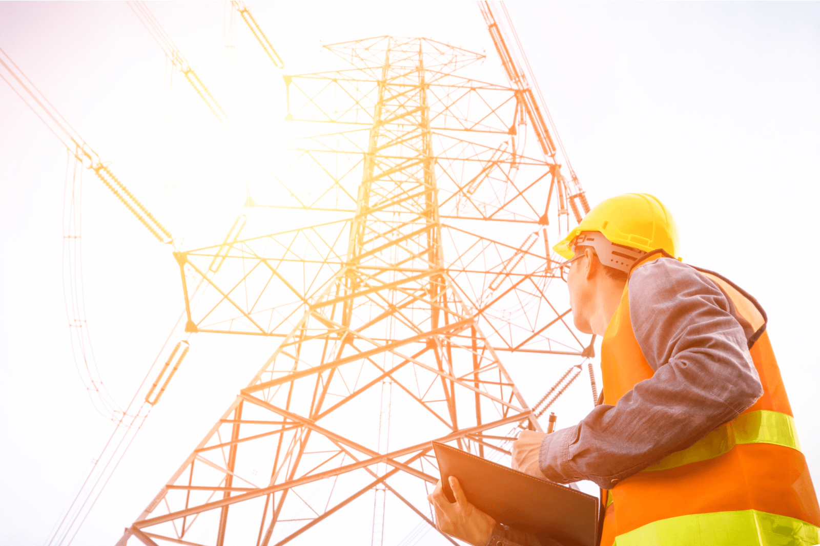 Man looking up at electrical lines on tower