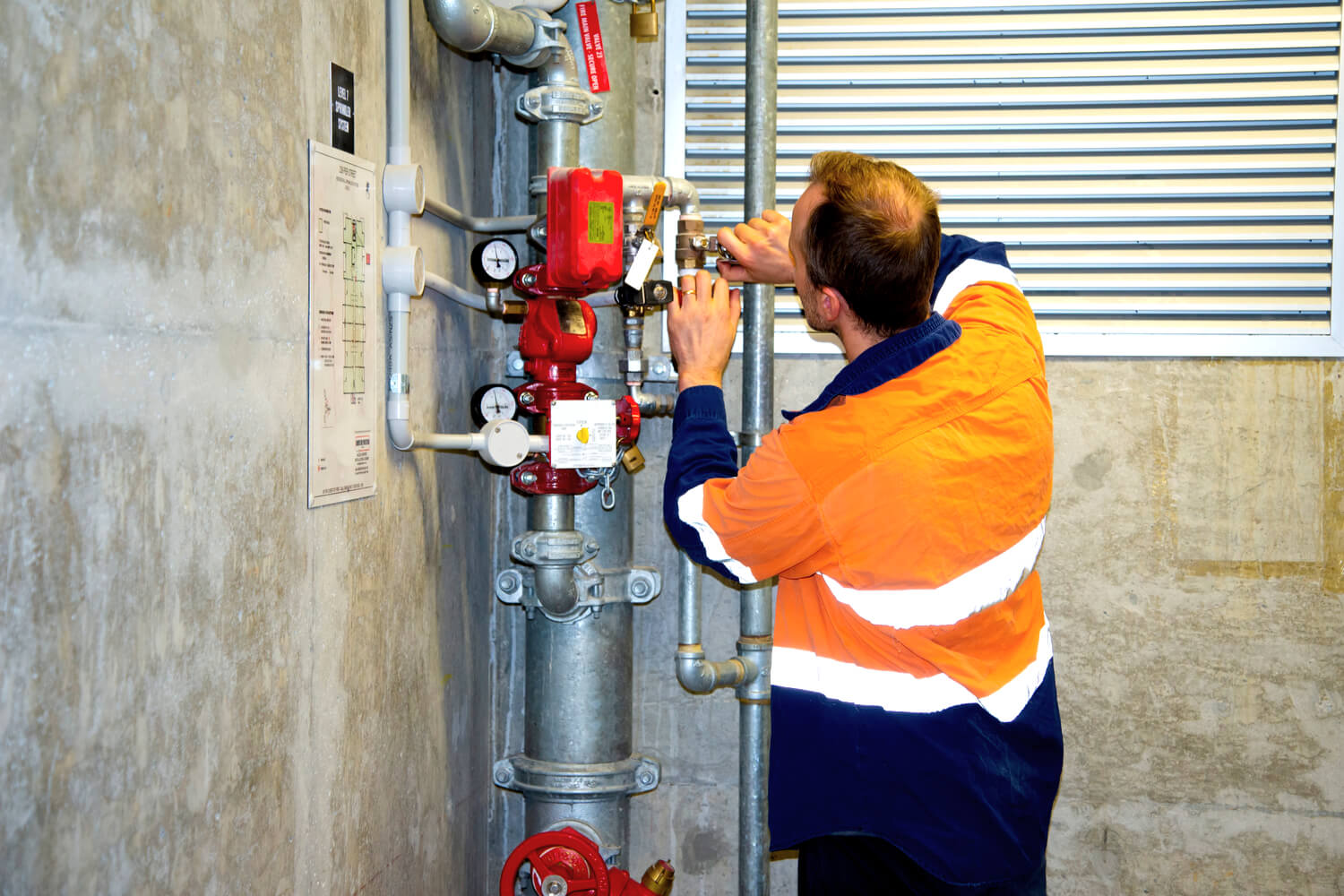 Man looking at pressurized water pipes in a commercial building